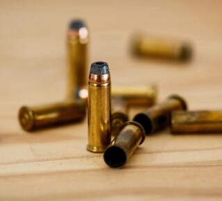 Detailed view of brass bullet shells scattered on a wood background.